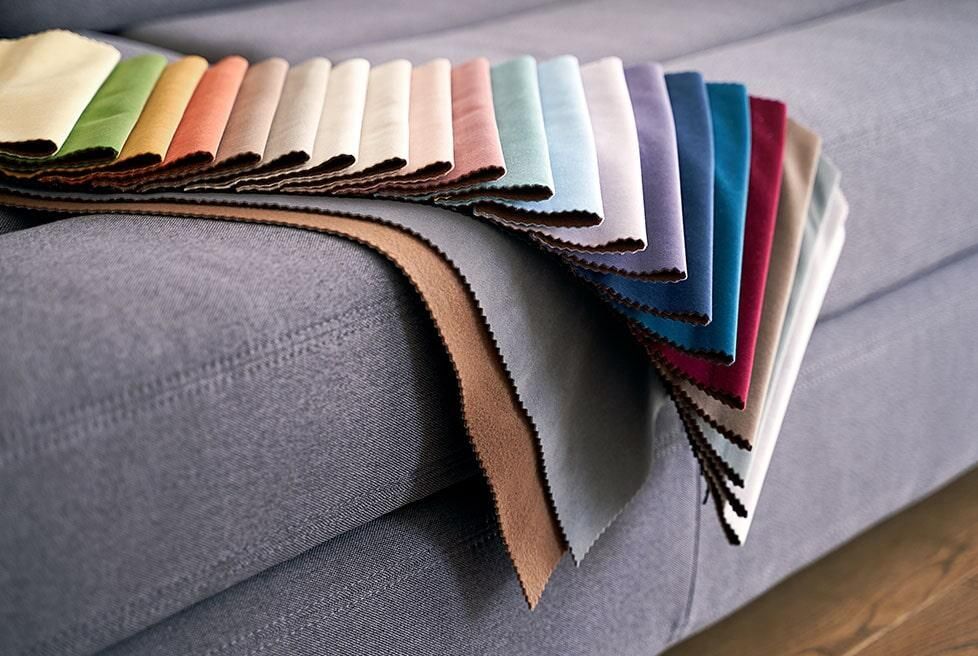 Un sofá con un montón de telas de diferentes colores encima.