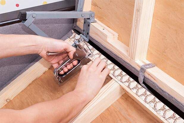 Una persona está usando una grapadora para grapar un mueble.