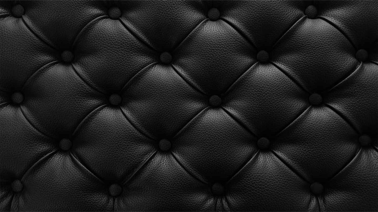 Un primer plano de un sofá de cuero negro con botones.