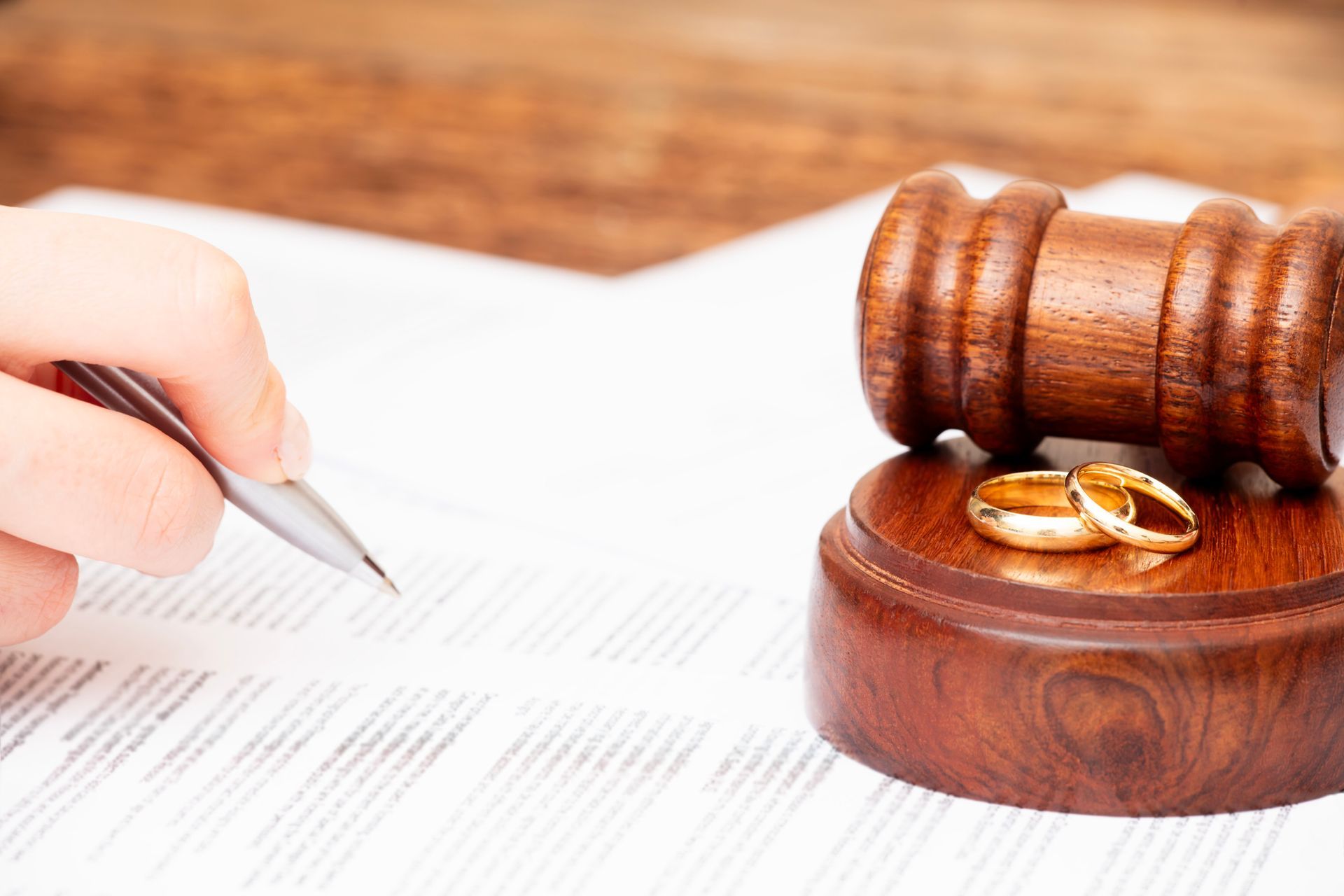 Divorce attorney paperwork with wedding rings and gavel on table, symbolizing legal separation