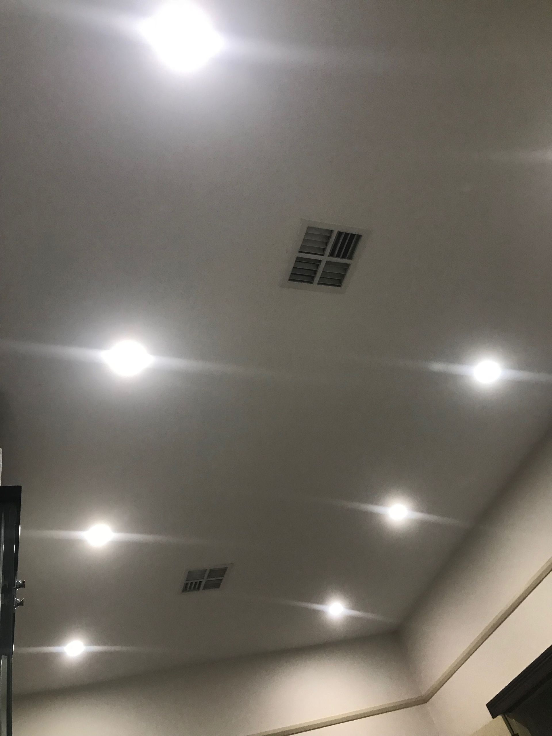 Ceiling with recessed lights and ventilation grilles in a softly lit room