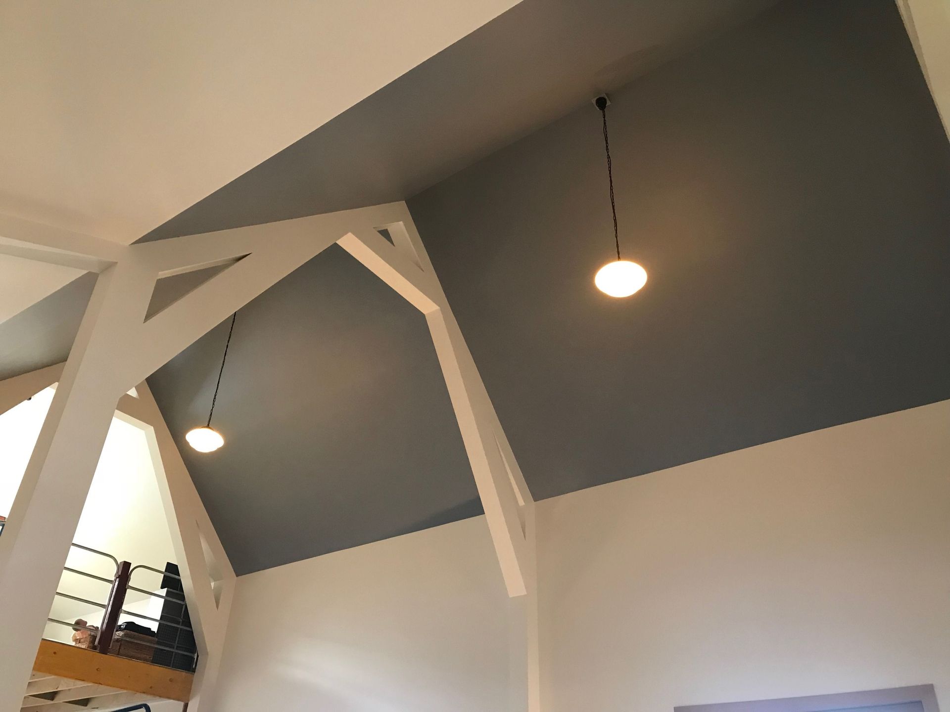 Modern interior with angled gray ceiling, white beams, and hanging pendant lights
