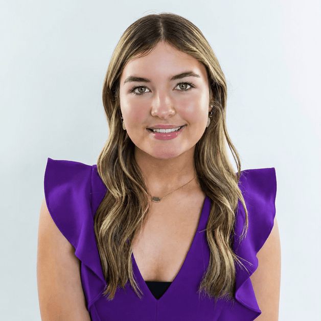 A woman in a pink dress and earrings is smiling for the camera.