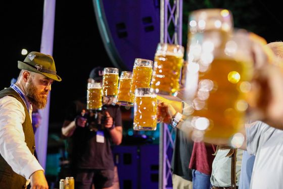 A group of people are standing on a stage holding beer mugs in their hands.