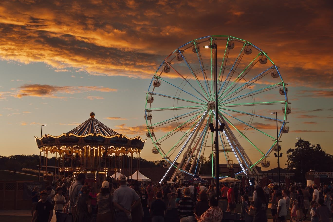 Ferris wheel and carousel at sunset with a crowd at a Oktoberfest