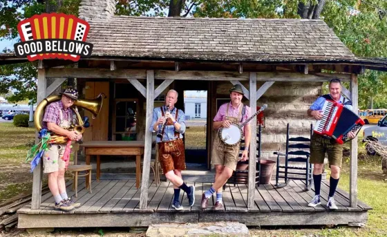 A group of men are standing on a porch playing instruments.