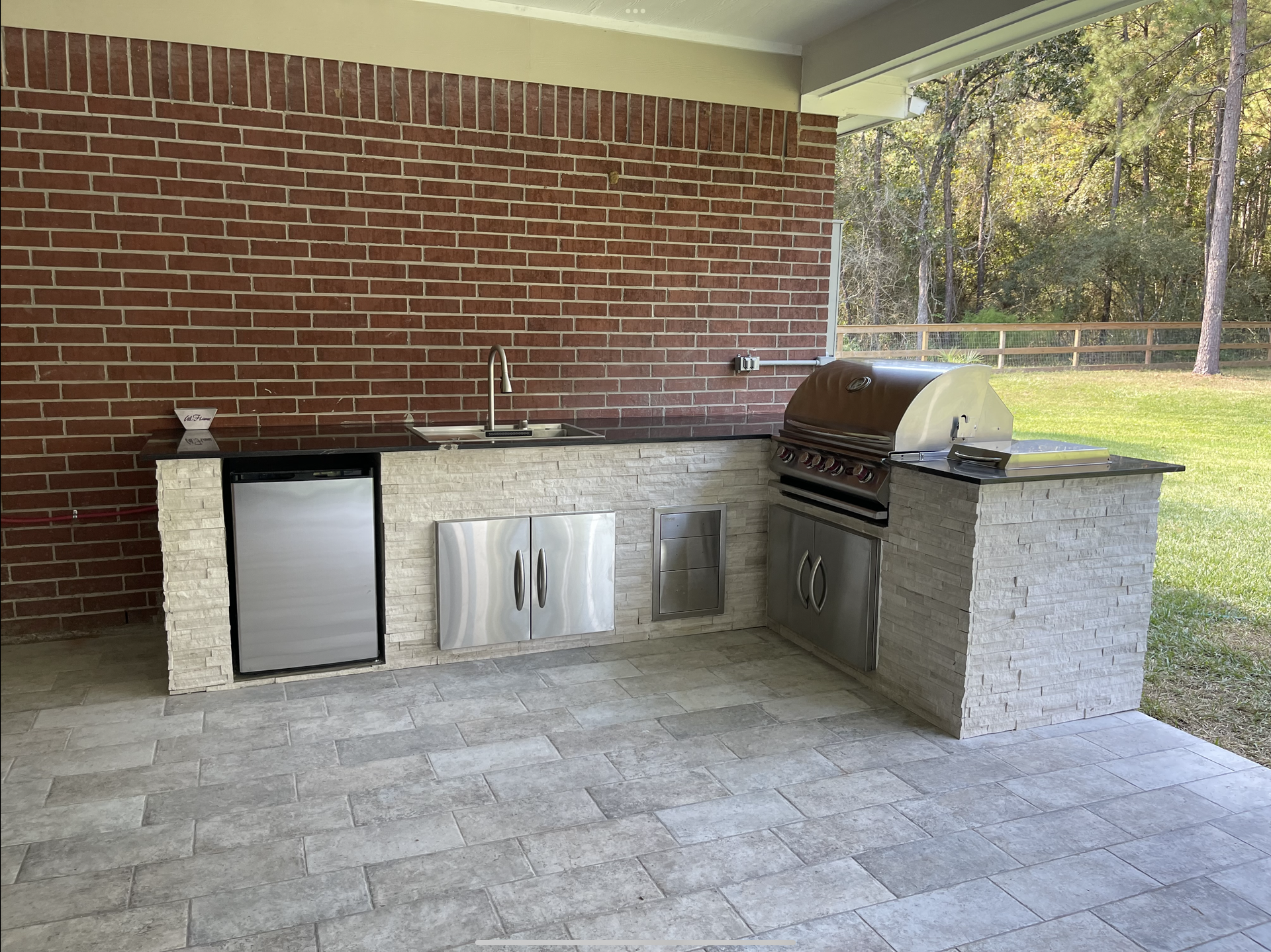 An outdoor kitchen with  brick and a built in grill