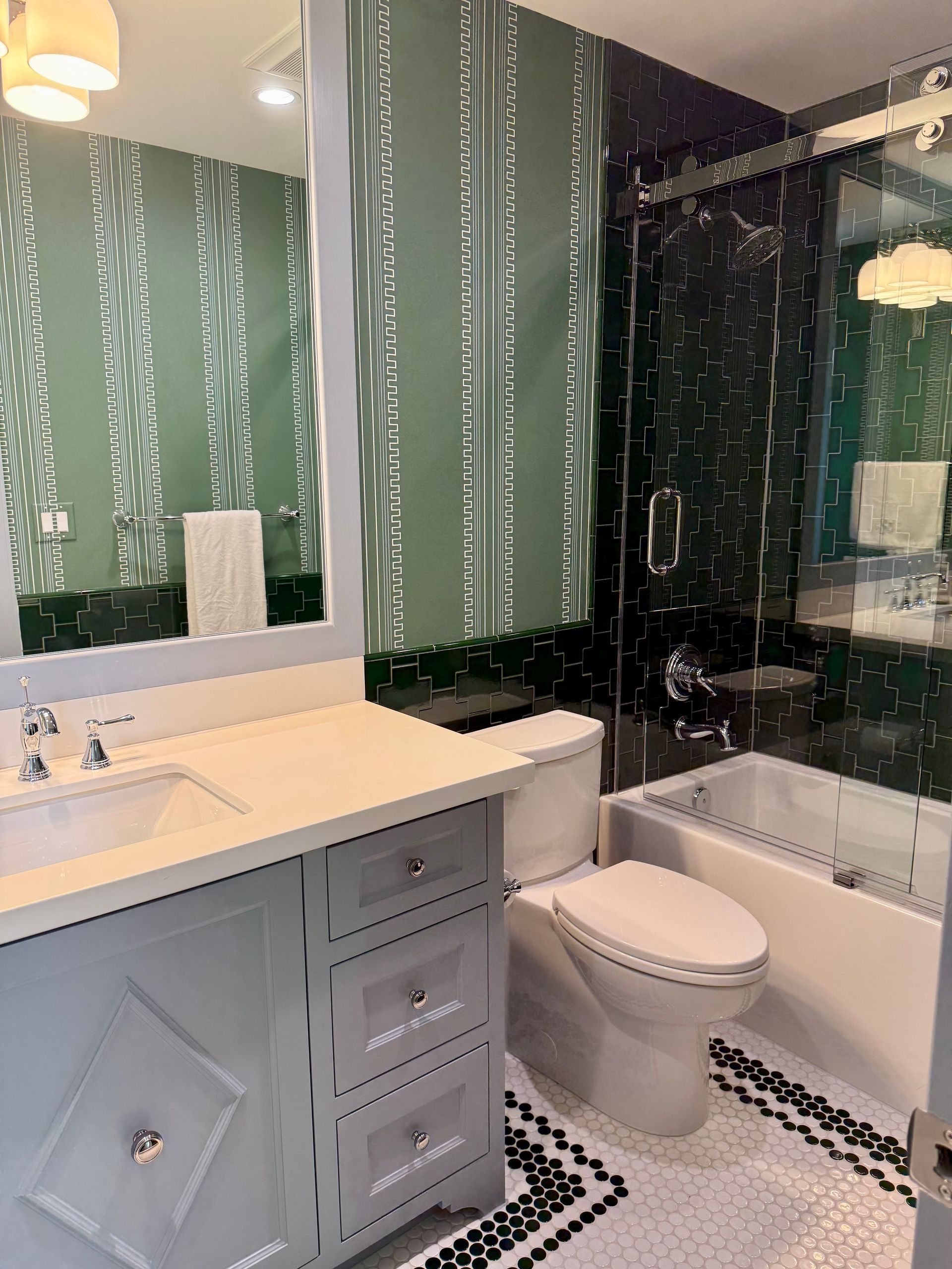 A bathroom with green tile shower, a toilet , sink , and bathtub.