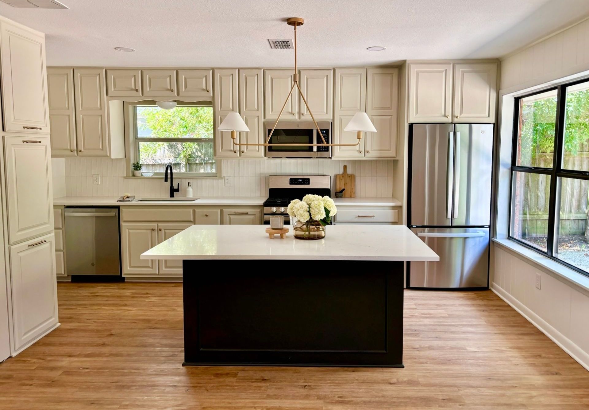 A kitchen with white cabinets , stainless steel appliances , and a large island.