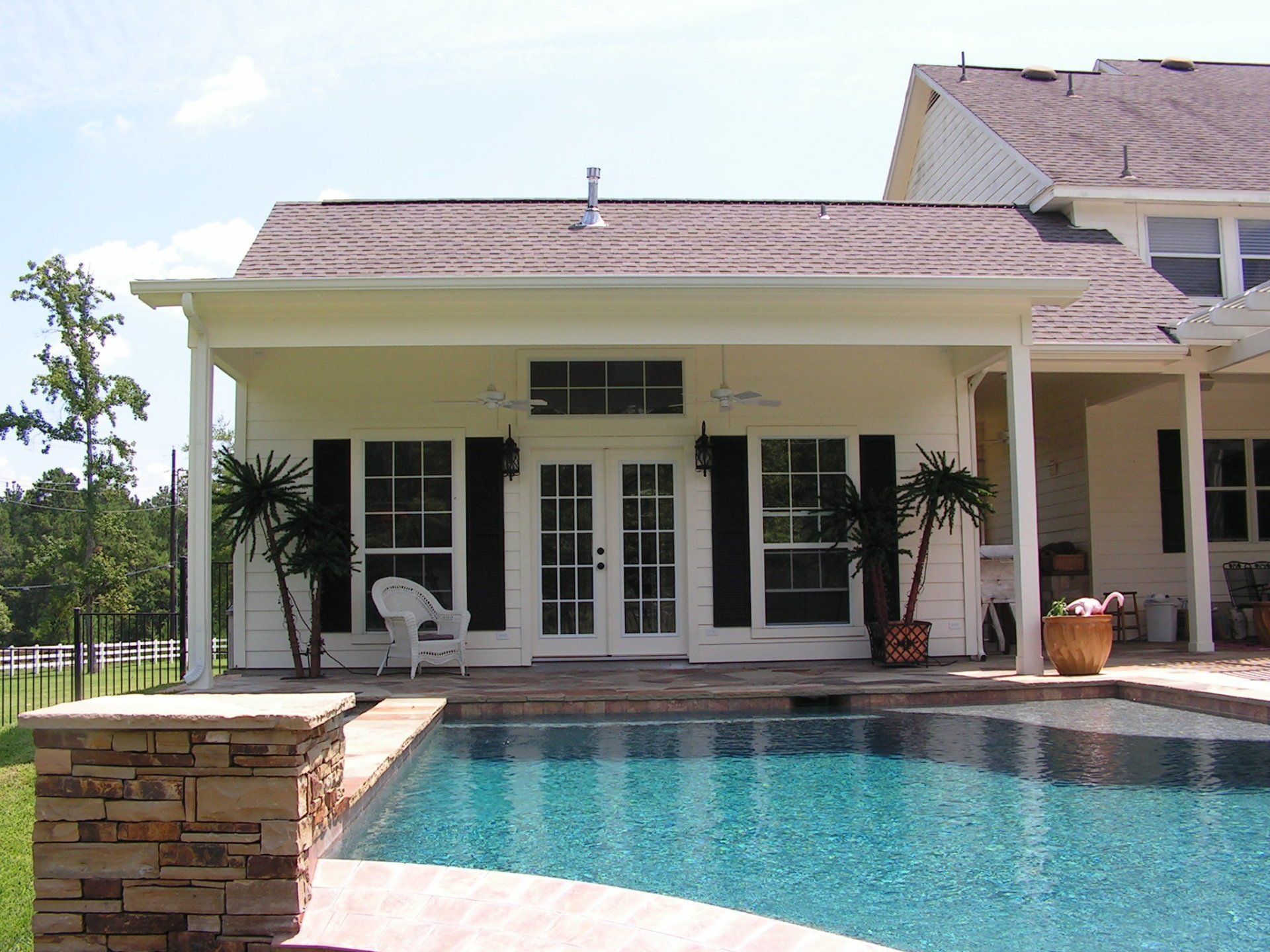 A white pool house with a swimming pool in front of it