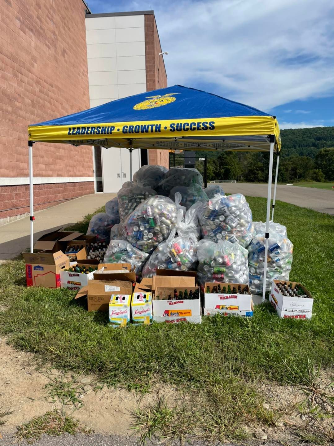 A large pile of bottle caps is sitting under a canopy in front of a building.