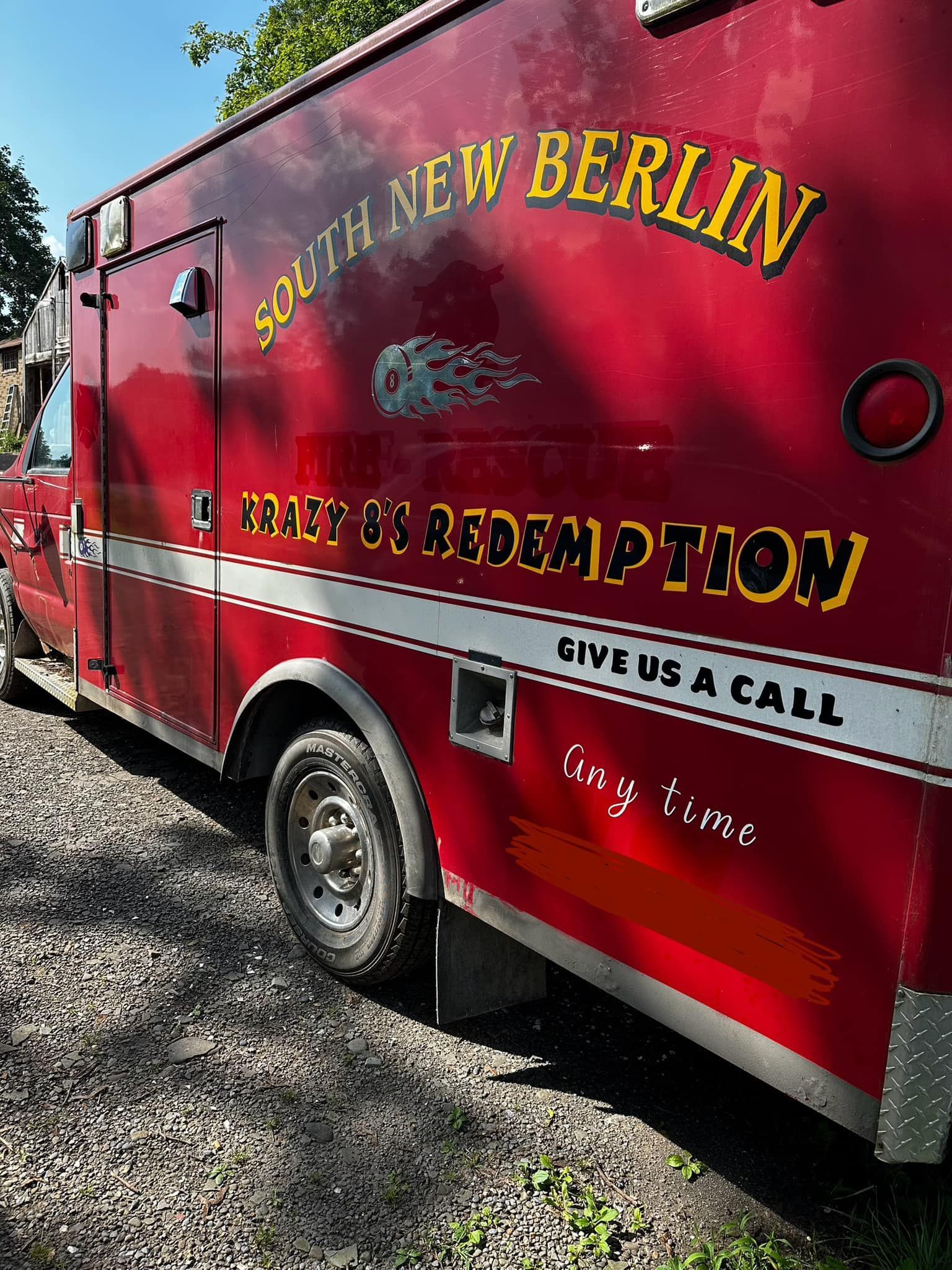 A red south new berlin ambulance is parked on gravel