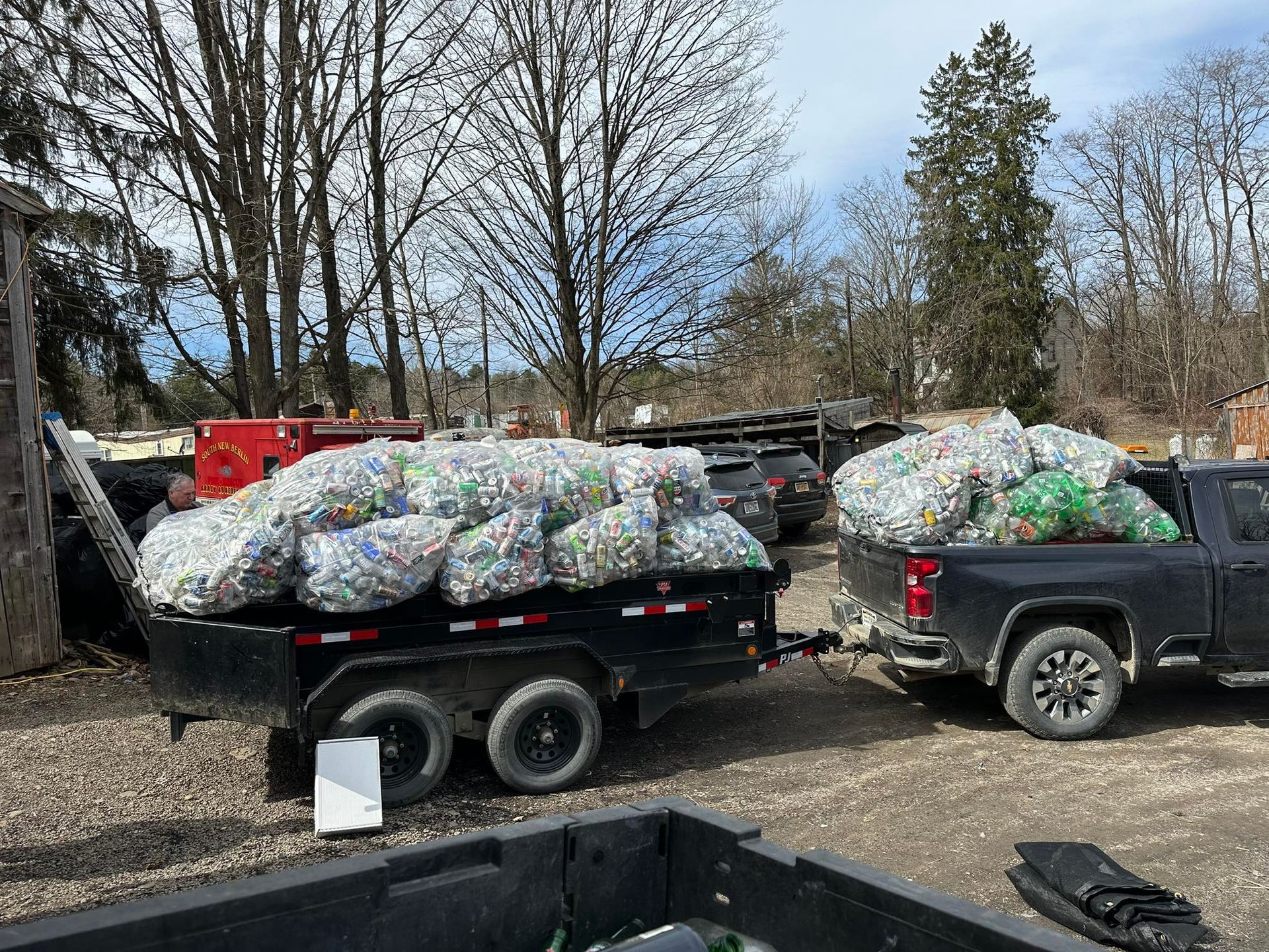 A truck is pulling a trailer filled with bags of recycling.