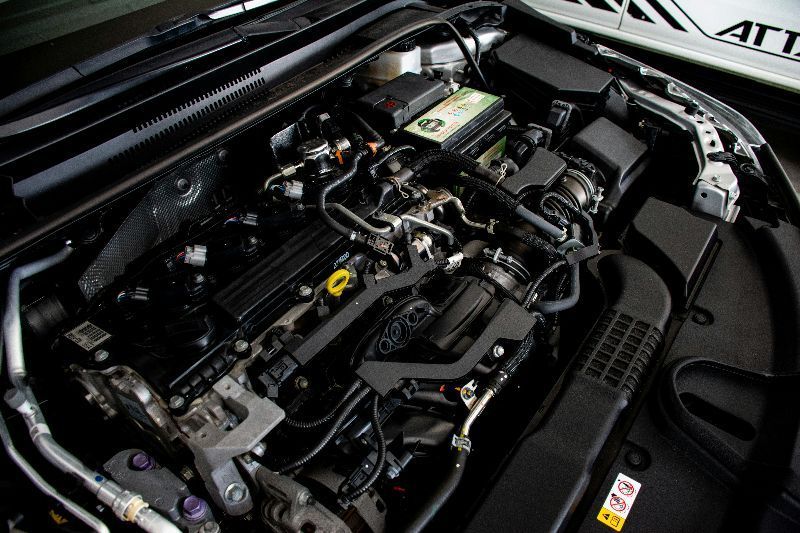 Open car engine bay with black components and hoses under the hood
