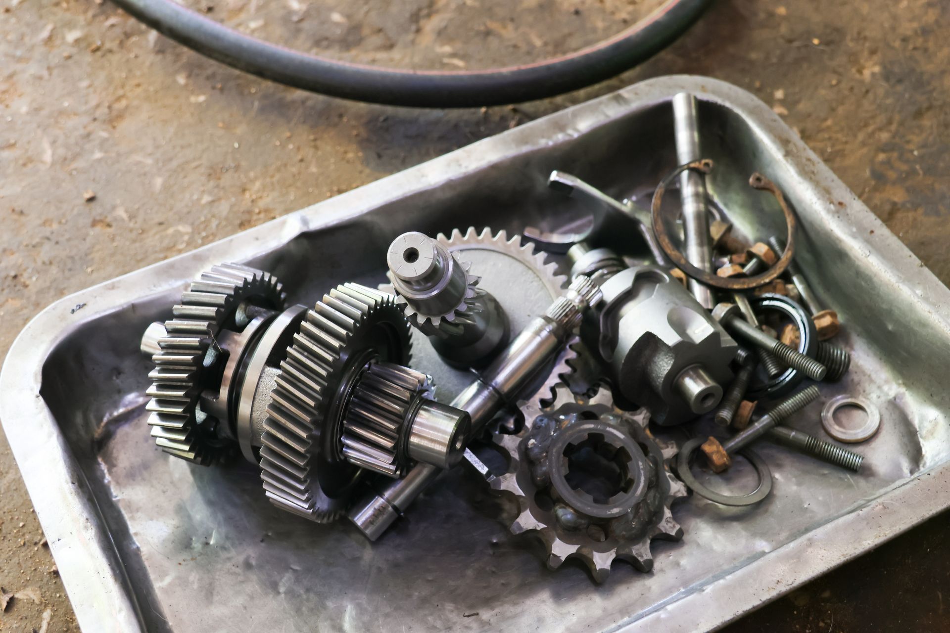 Metal gears and mechanical parts in a shallow tray on a workbench
