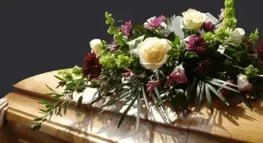 Flowers arranged on a closed wooden coffin in a solemn funeral setting