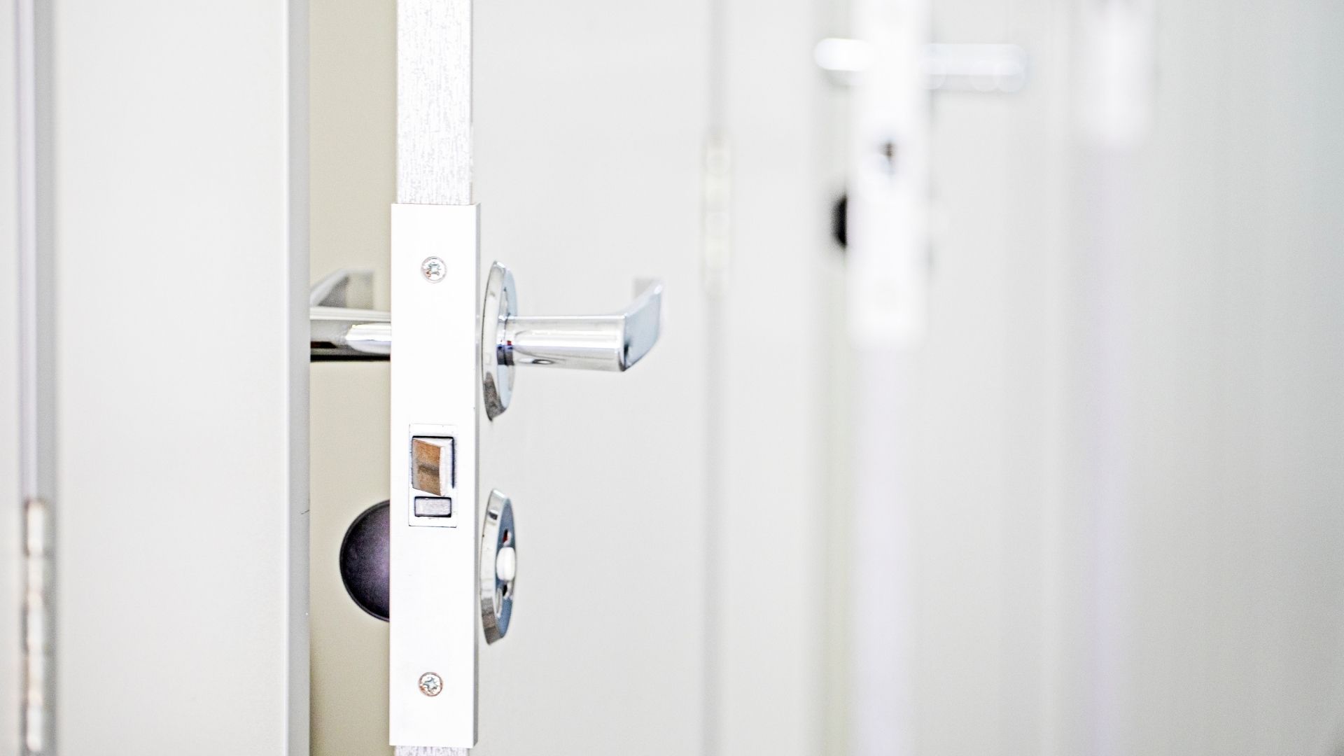 Hands using a screwdriver to repair an old brass door lock on a wooden door