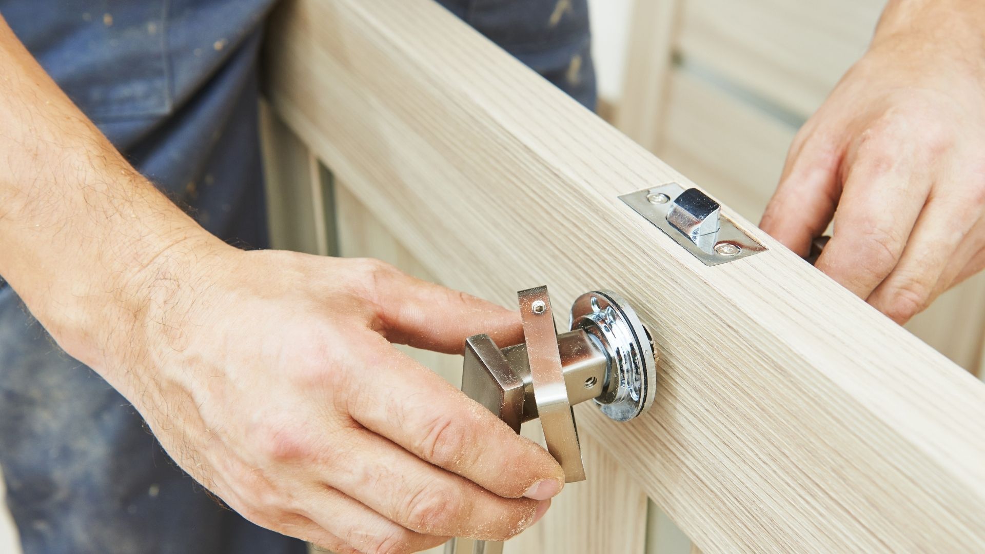 Close-up of a brass door lock and key on a dark wooden door with a bright window nearby