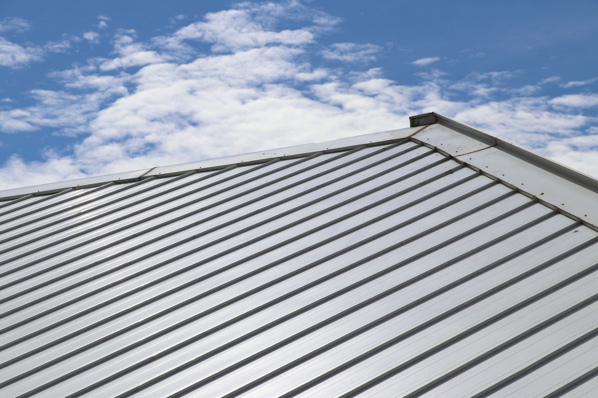 A close up of a metal roof with a blue sky in the background.
