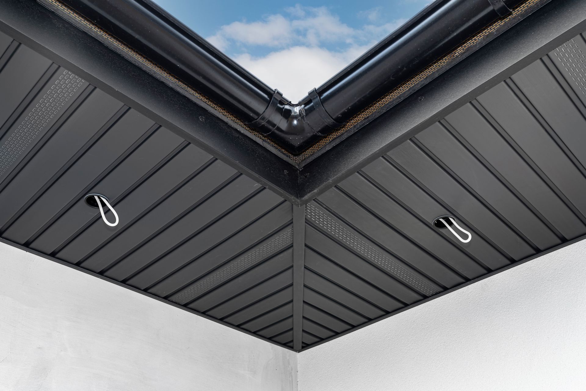 A black ceiling with a skylight in the corner of it.