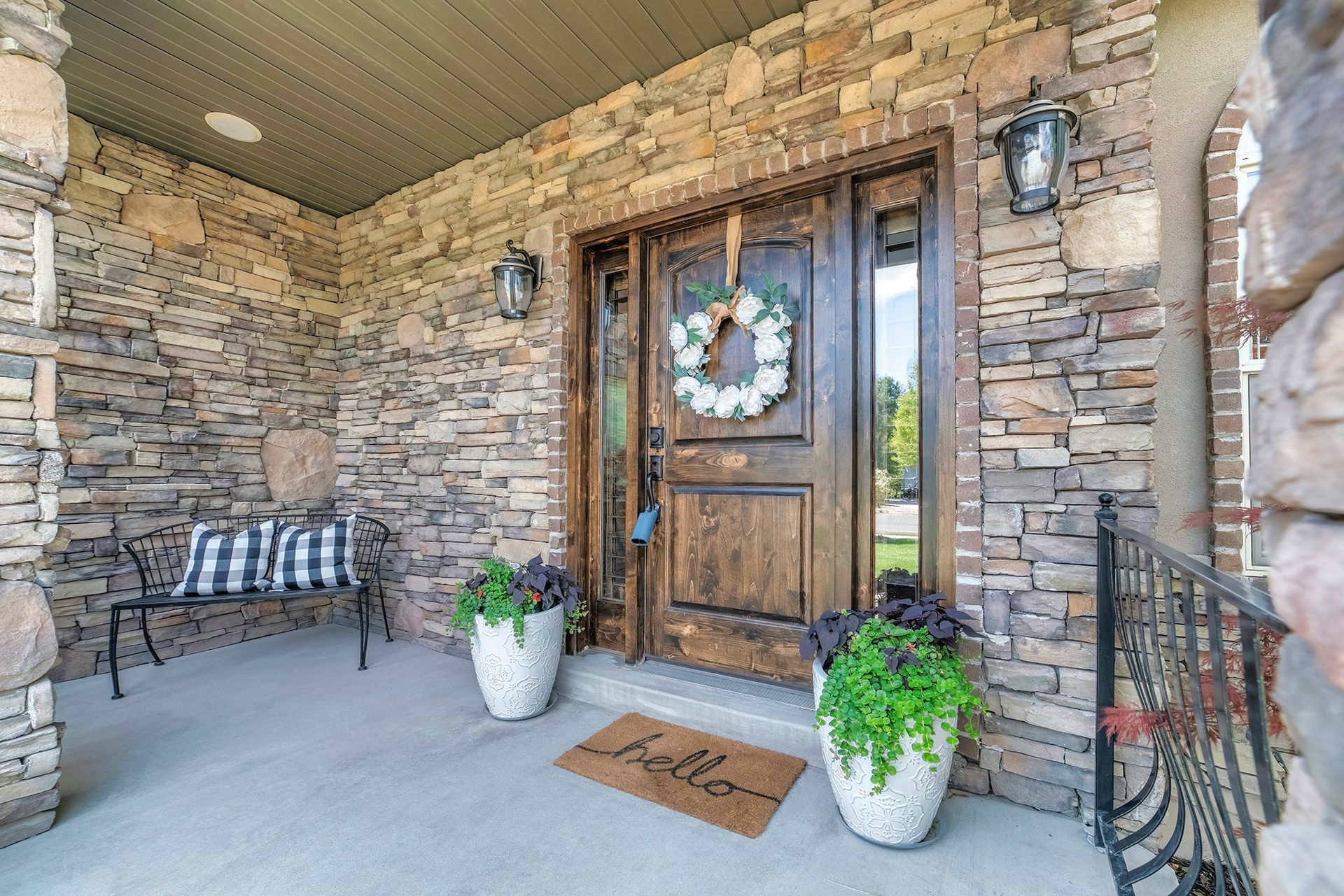 The front door of a house with a wreath on it and potted plants on the porch.