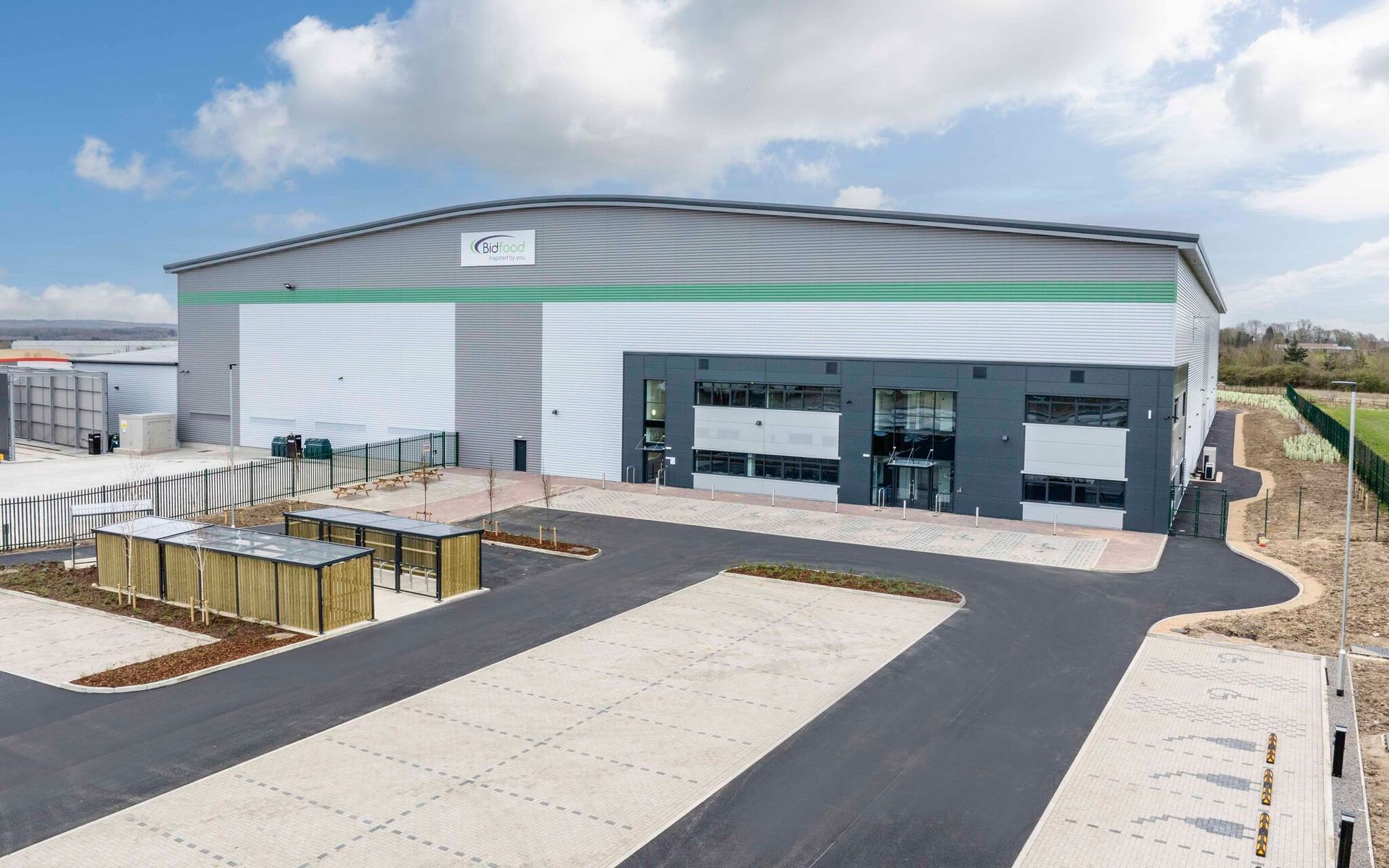 Modern industrial warehouse and office facility with large loading and parking areas, viewed from the front exterior on a clear day.