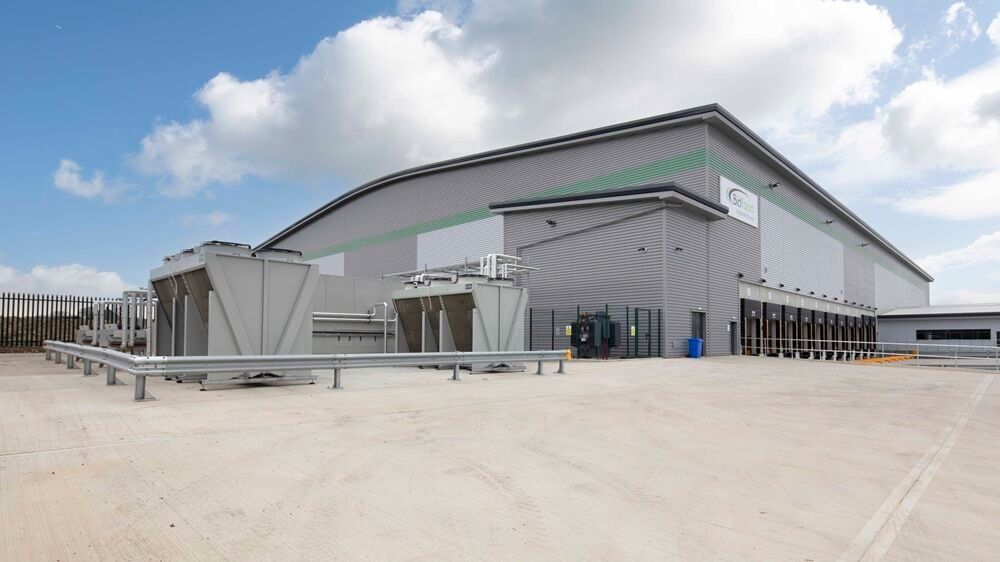Modern industrial warehouse and office facility with large loading areas, viewed from the side exterior on a clear day.
