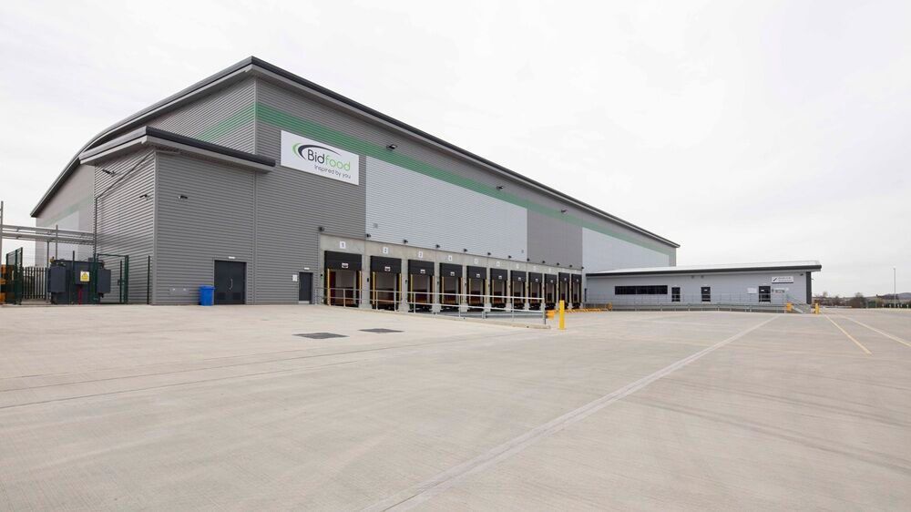 Modern industrial warehouse and office facility with large loading areas, viewed from the side exterior on a clear day.