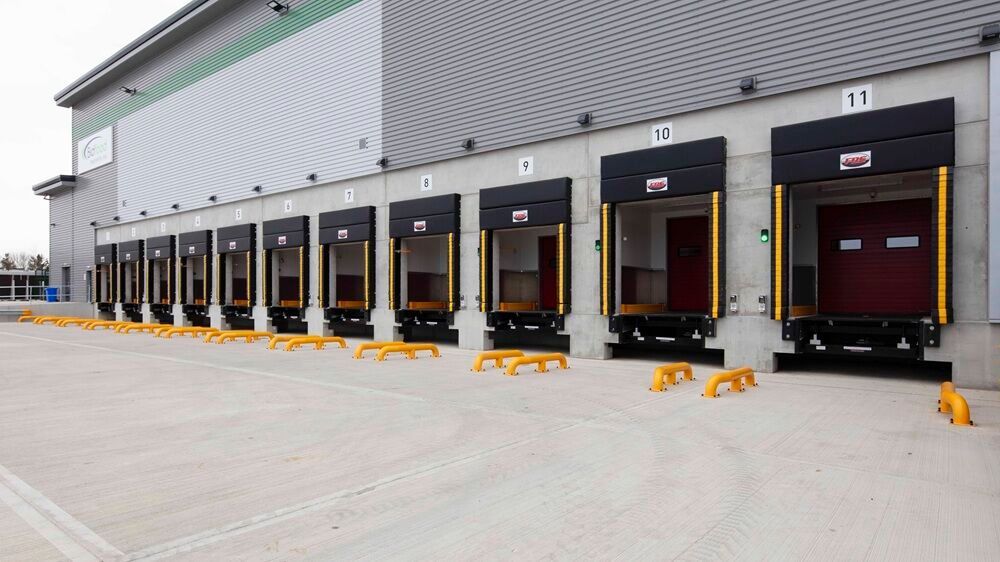 Modern industrial warehouse loading areas, viewed from the side exterior on a clear day.