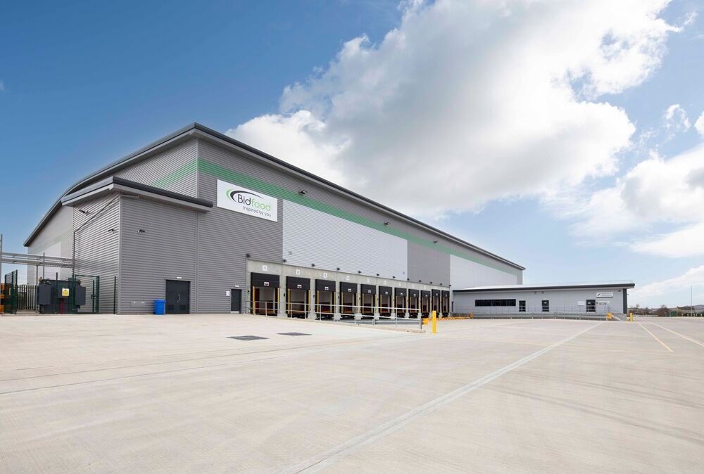 Modern industrial warehouse and office facility with large loading areas, viewed from the side exterior on a clear day.
