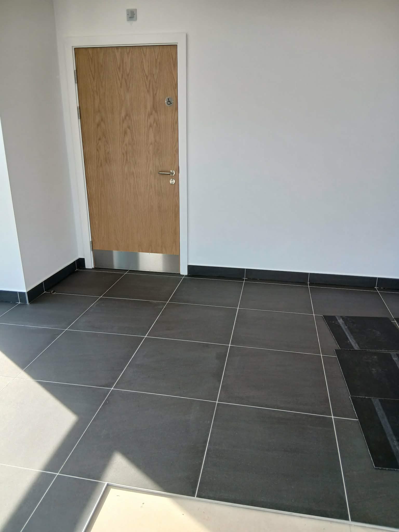 Clean internal entrance area with tiled floor and wooden door