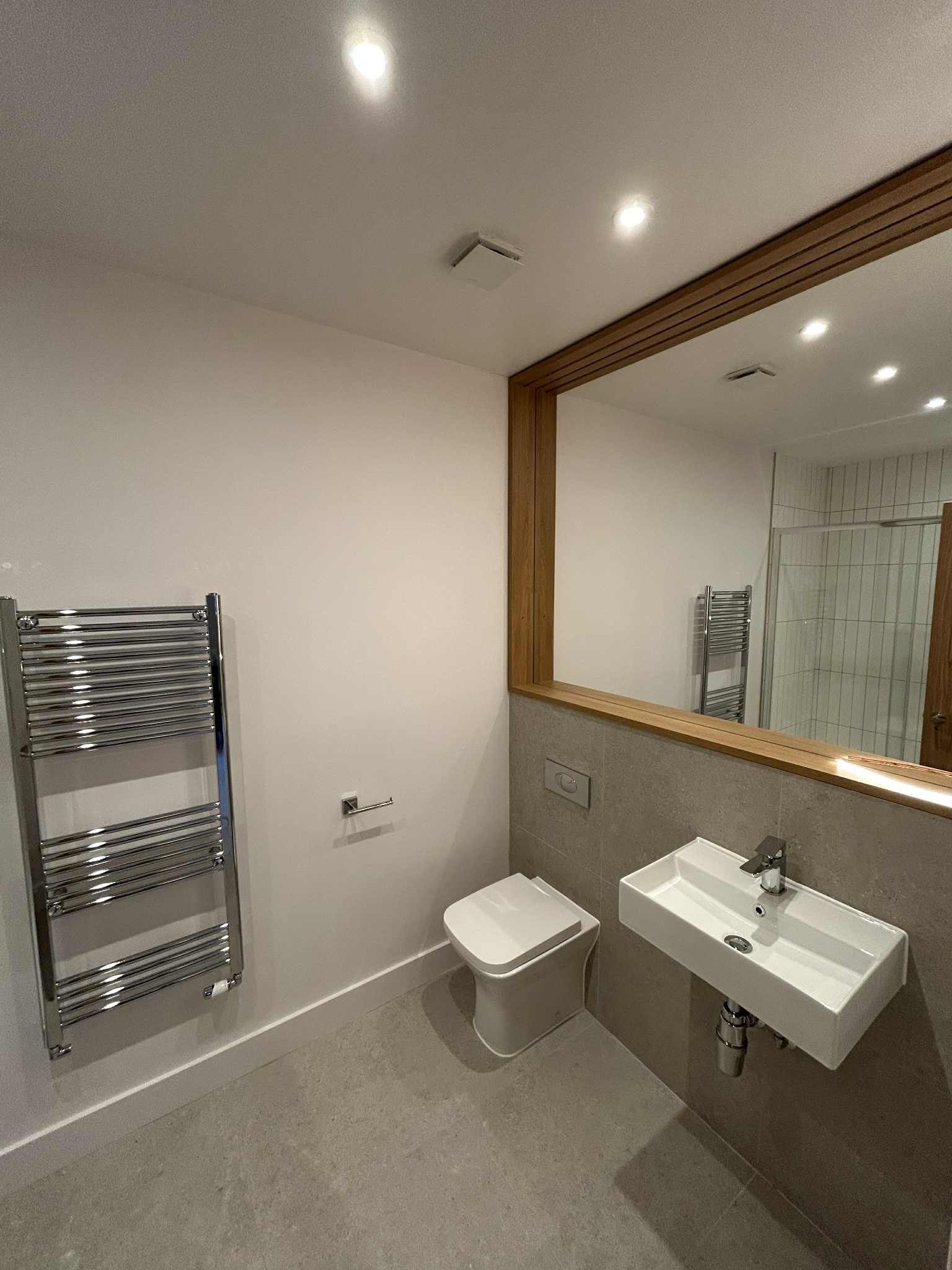 Clean modern bathroom with large wall mirror and heated towel rail