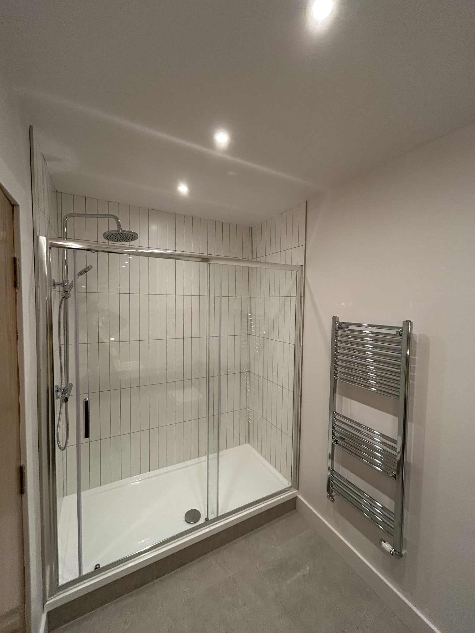 Modern tiled bathroom with glass shower enclosure after cleaning 