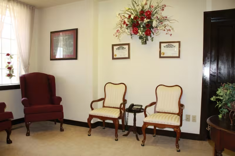 Waiting room with red and cream chairs, framed art, and floral wall decoration on beige walls