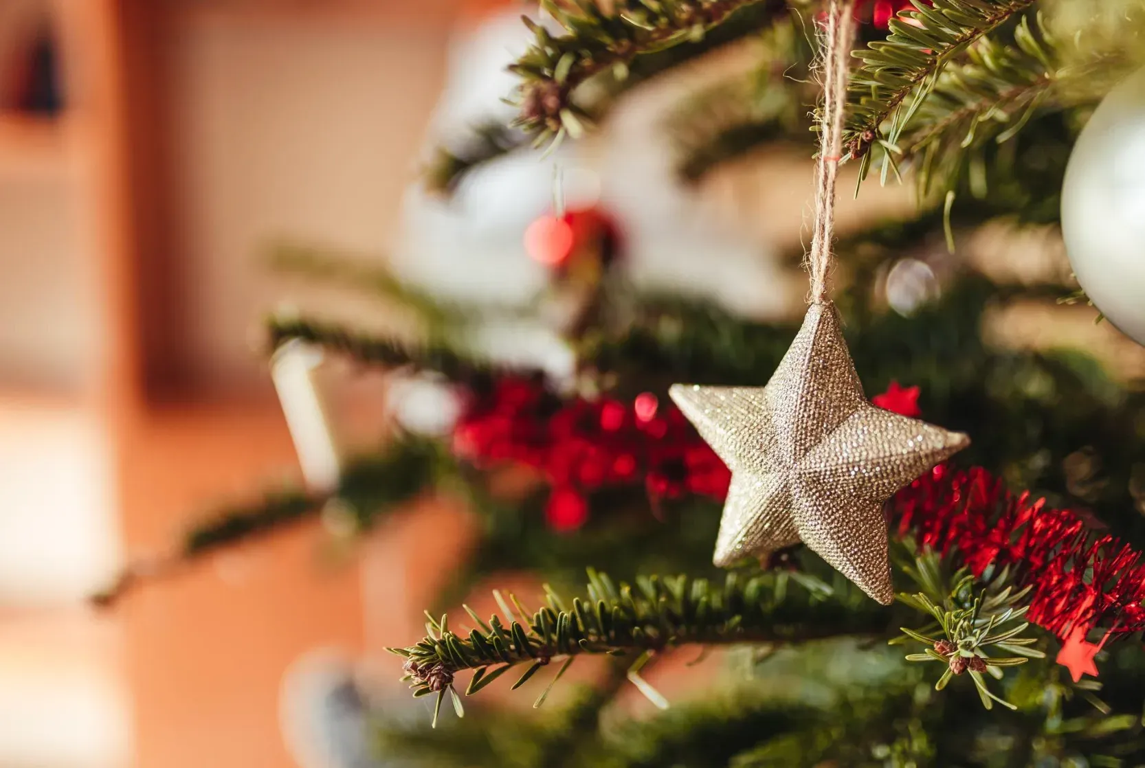 Estrela dourada pendurada em galho de árvore de Natal decorada, representando o clima natalino