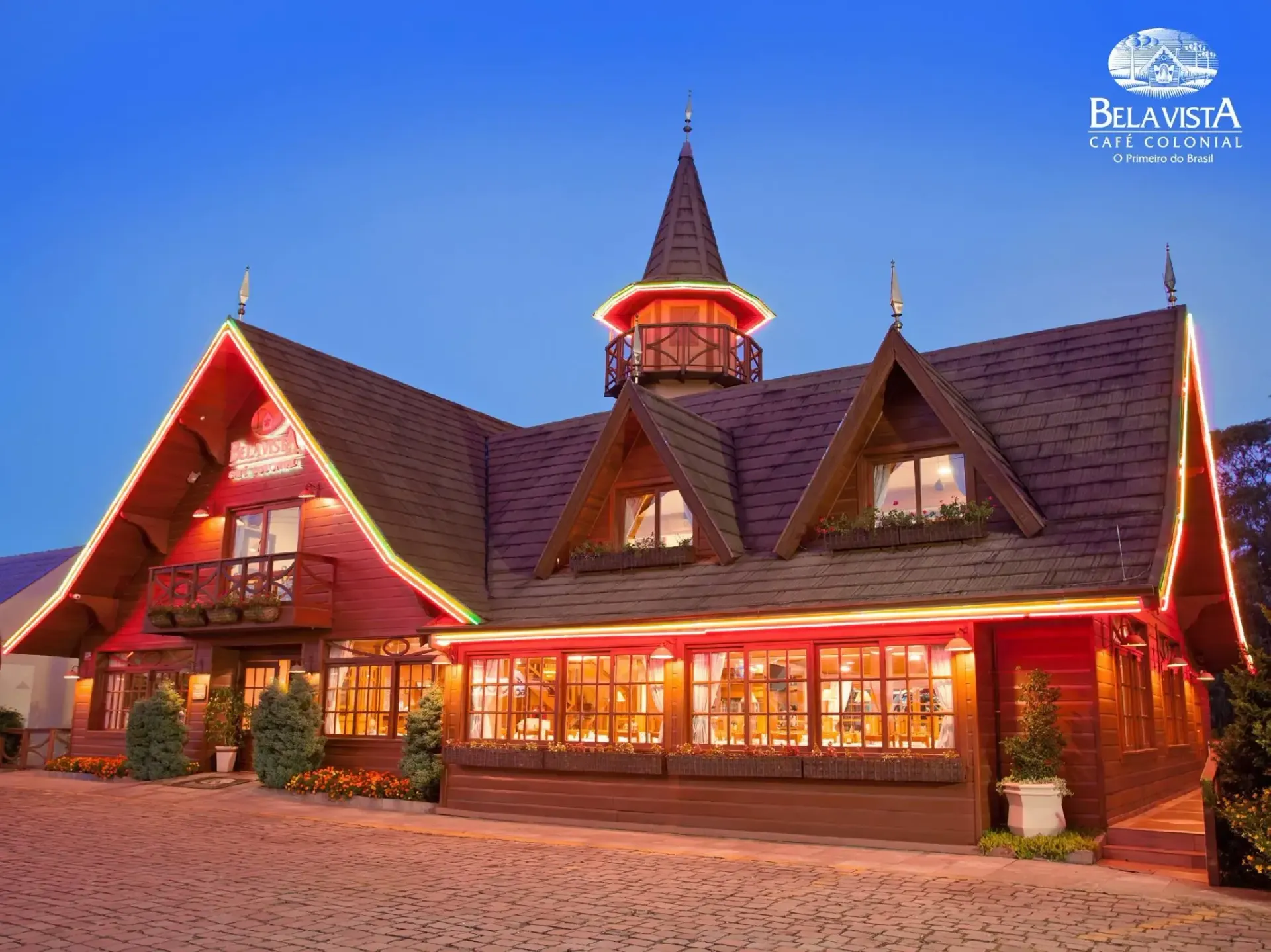 Fachada iluminada do Café Colonial Bela Vista, o primeiro café colonial do Brasil, em Gramado, ao anoitecer.