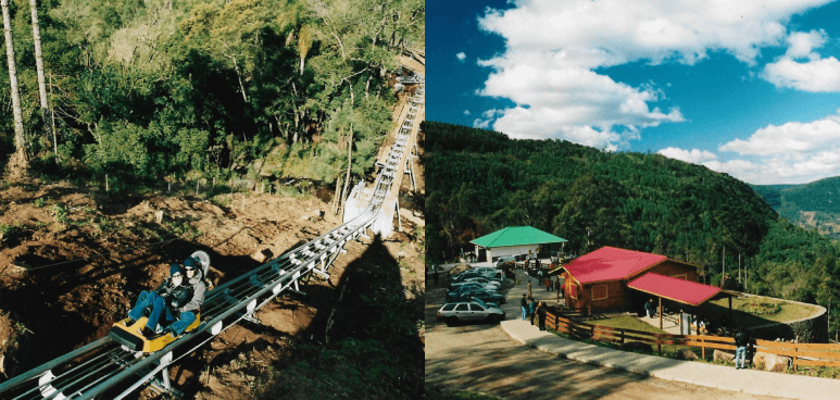 Teleférico subindo uma encosta íngreme ao lado de um vale pitoresco com telhados coloridos abaixo.