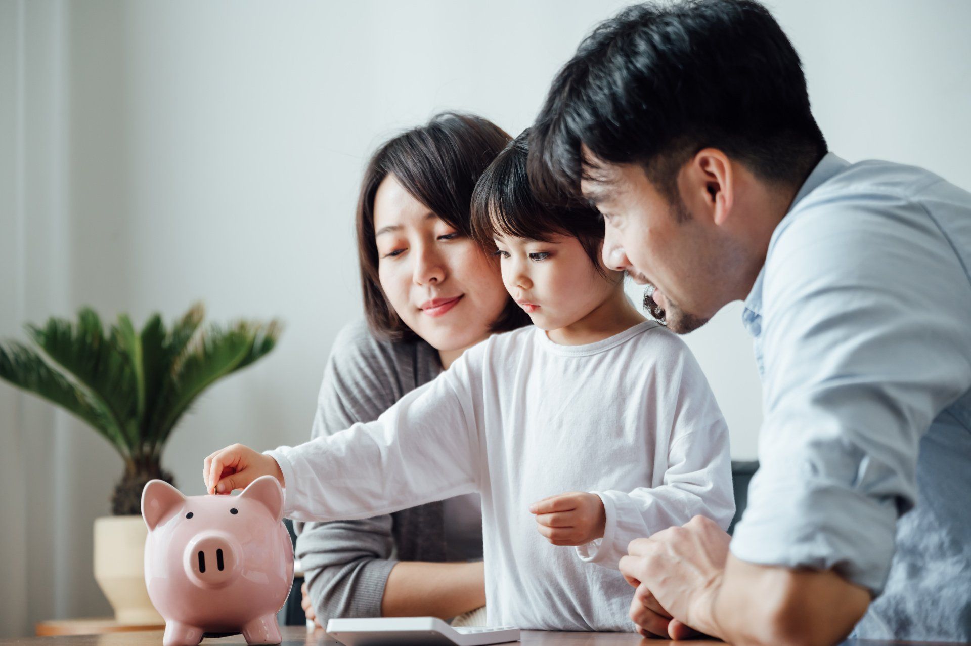 Family with a child putting a coin into a piggy bank.