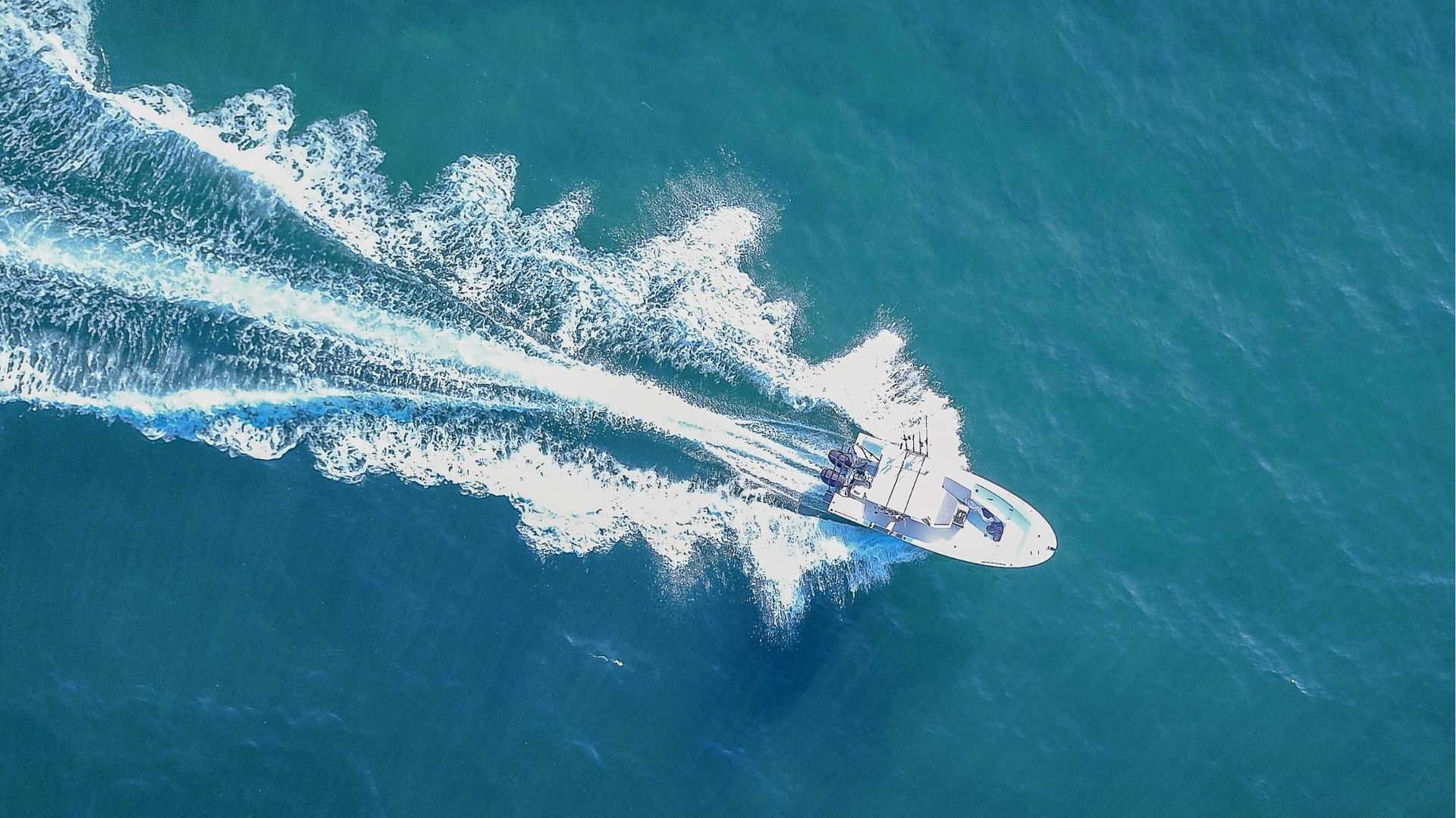 Speedboat racing across blue water, leaving a long white wake behind.
