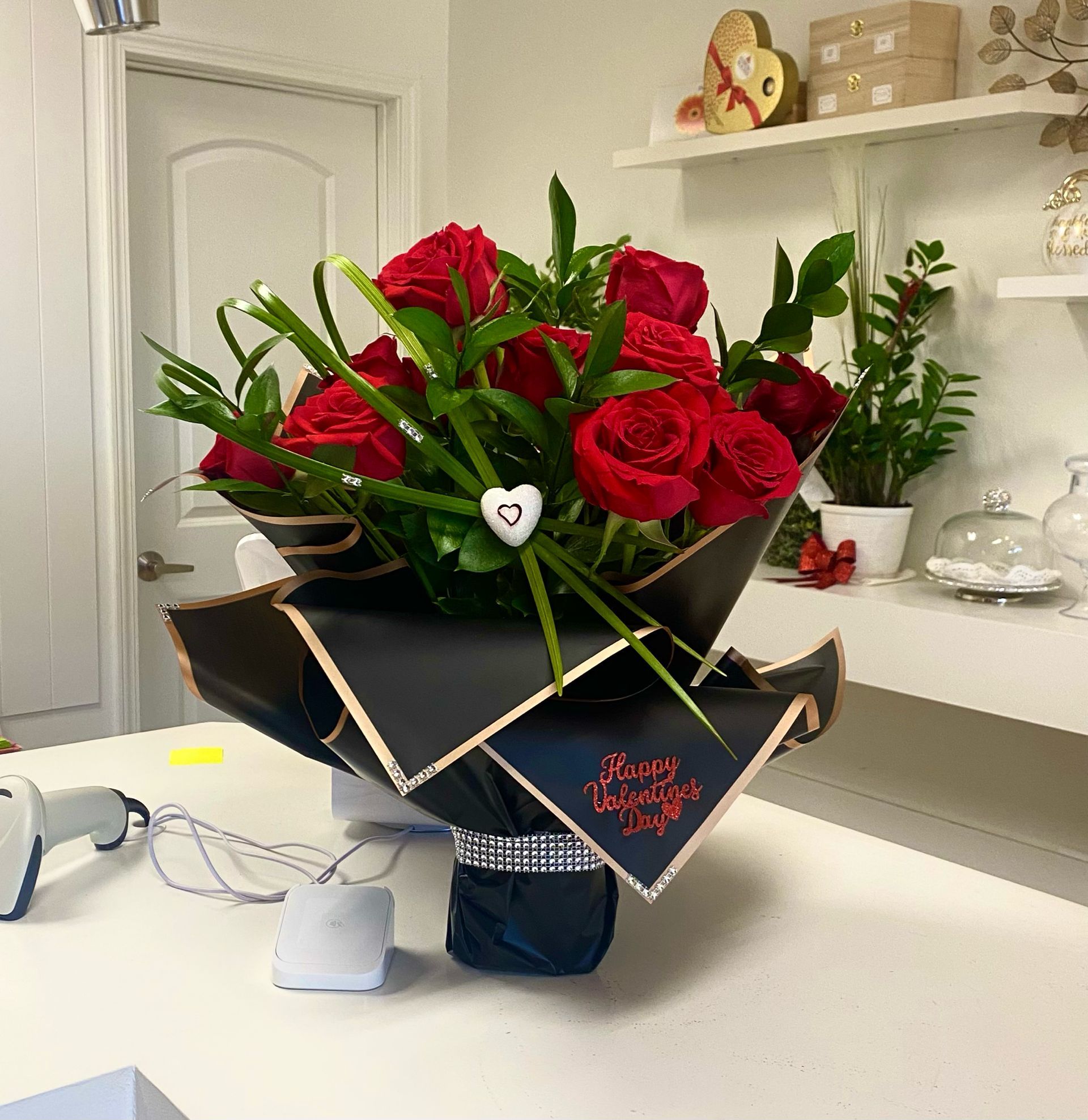 Luxury Bouquet of red roses in a black and gold decorative arrangement on a countertop.