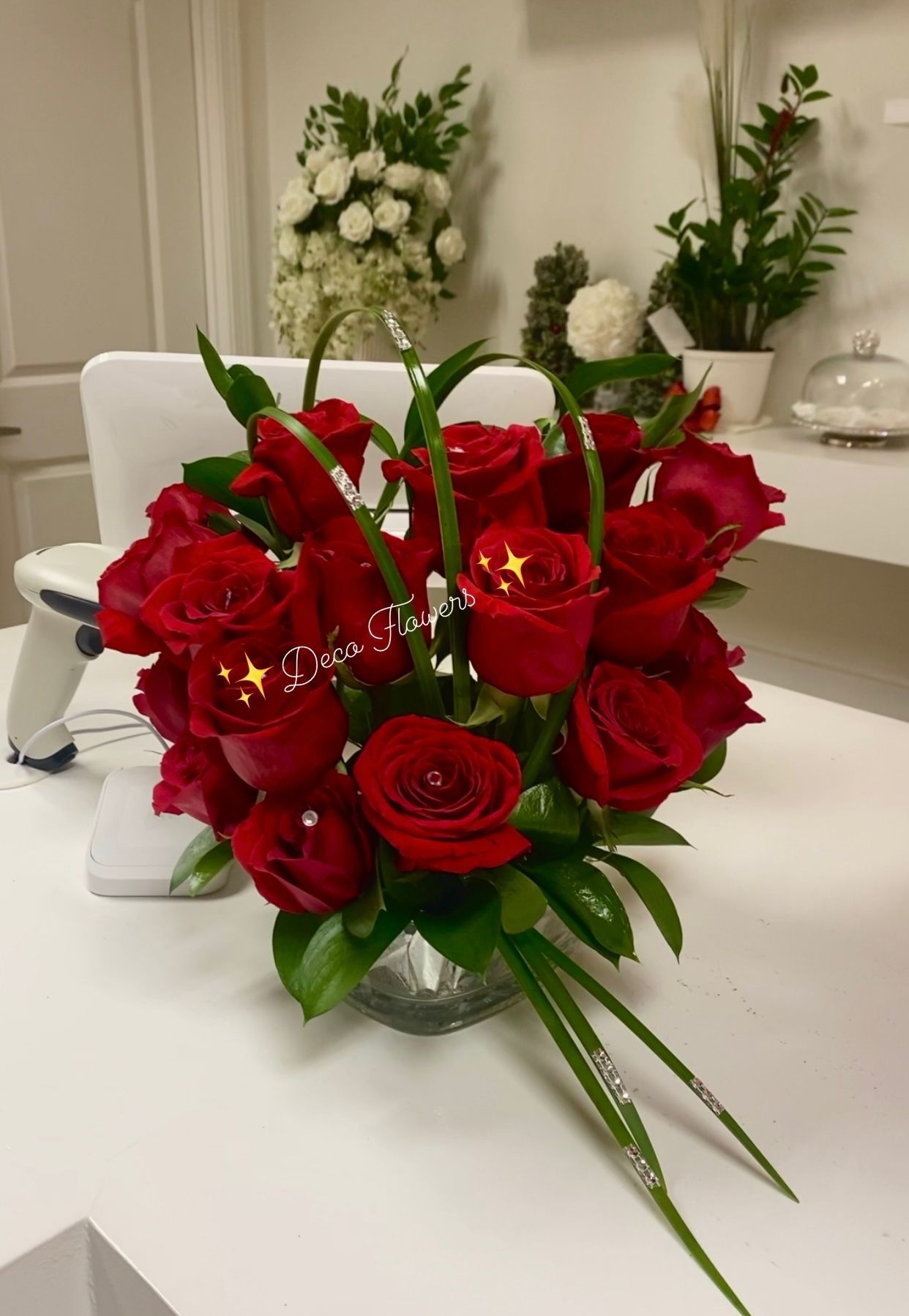 Luxury & premium Red roses in a silver vase with greenery on a white surface,