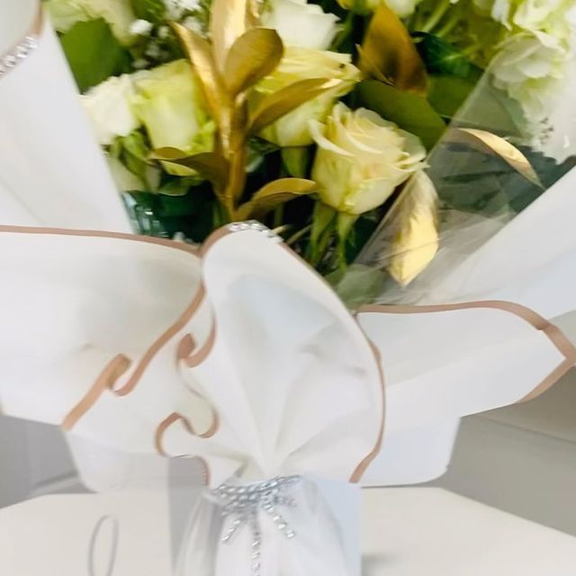 Luxury Bouquet of white roses and gold leaves in white and gold wrapping.