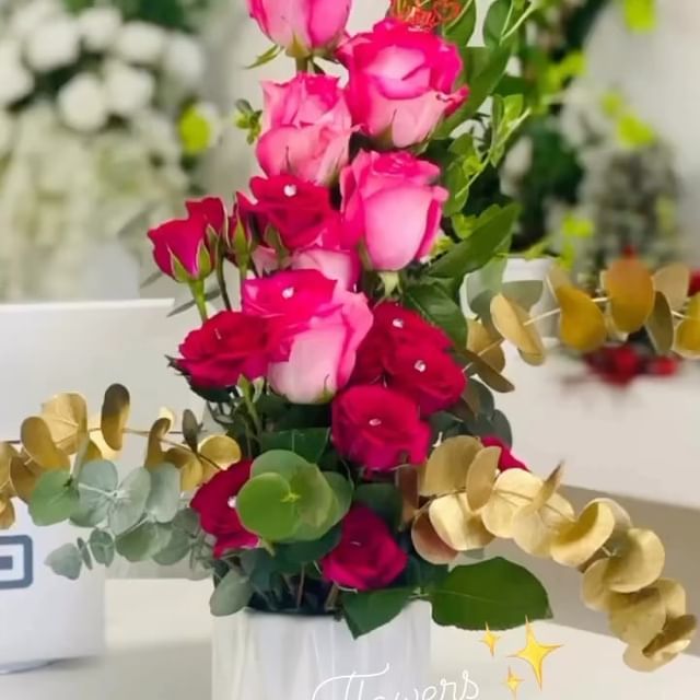 Premium Pink and red roses in a white vase with gold and green foliage.