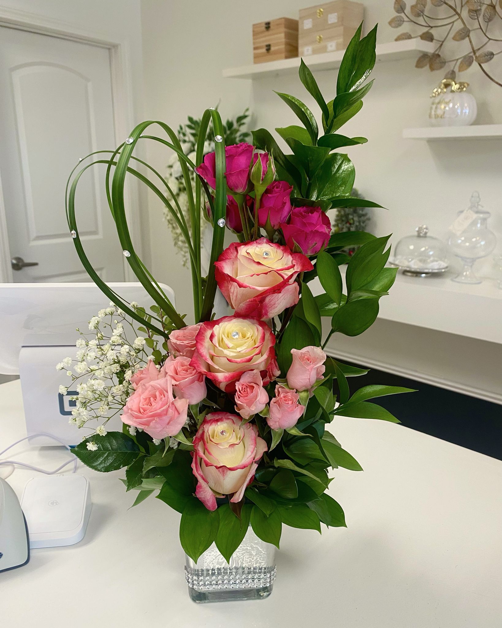 Luxury Floral arrangement with pink and cream roses, carnations, and greenery in a glass vase.