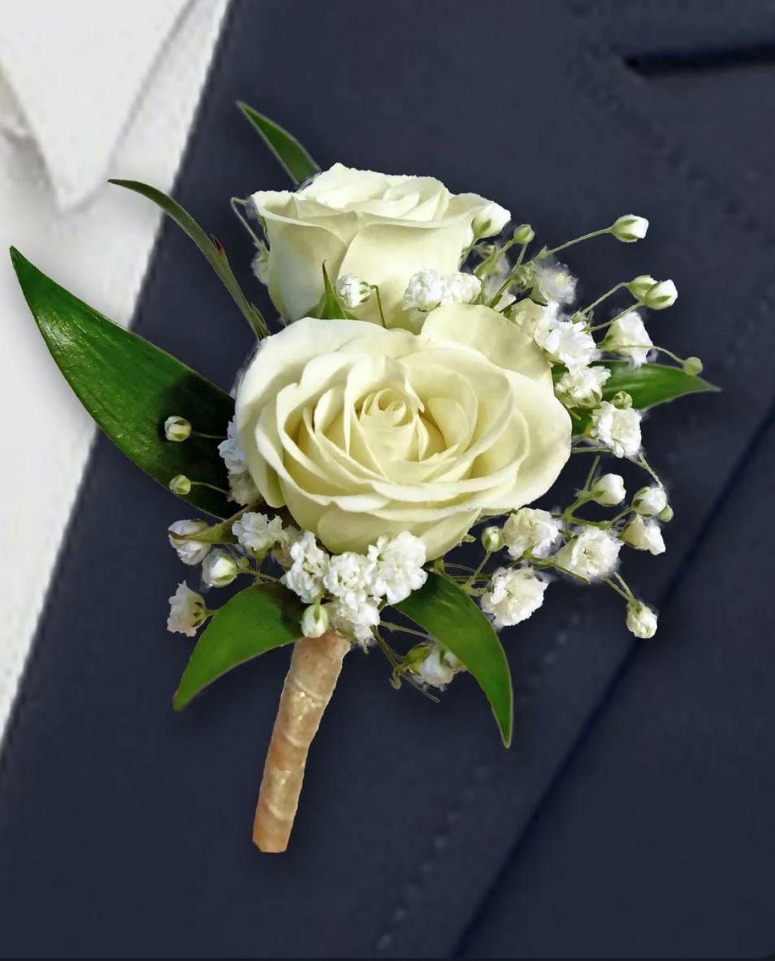 White rose boutonniere pinned to a dark blue suit jacket.