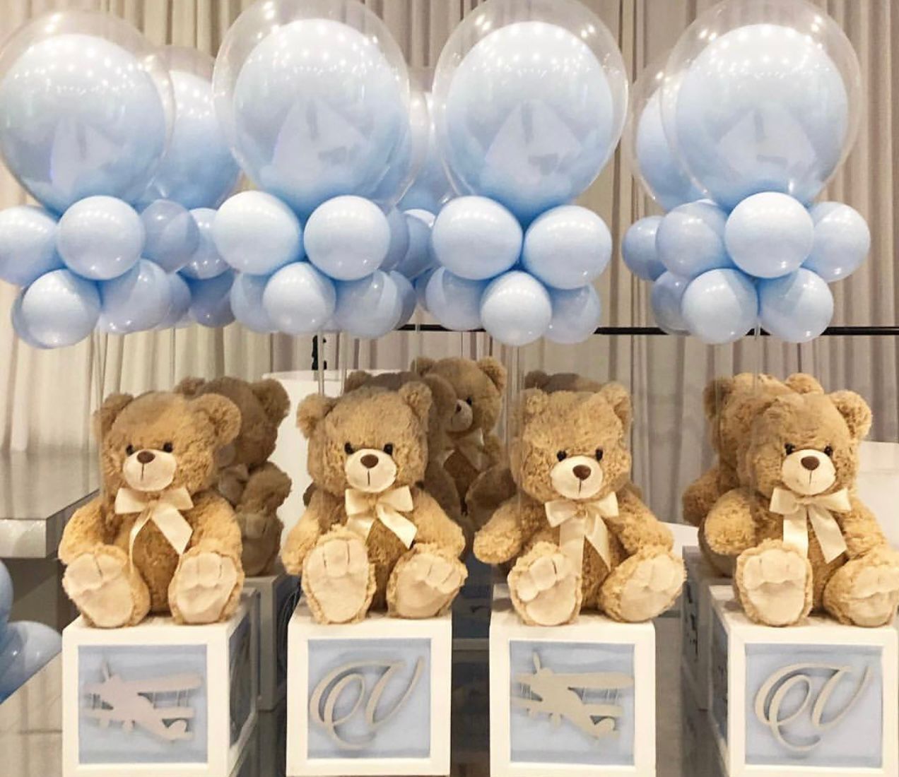 Blue balloon decorations and teddy bears on blocks for a baby shower.