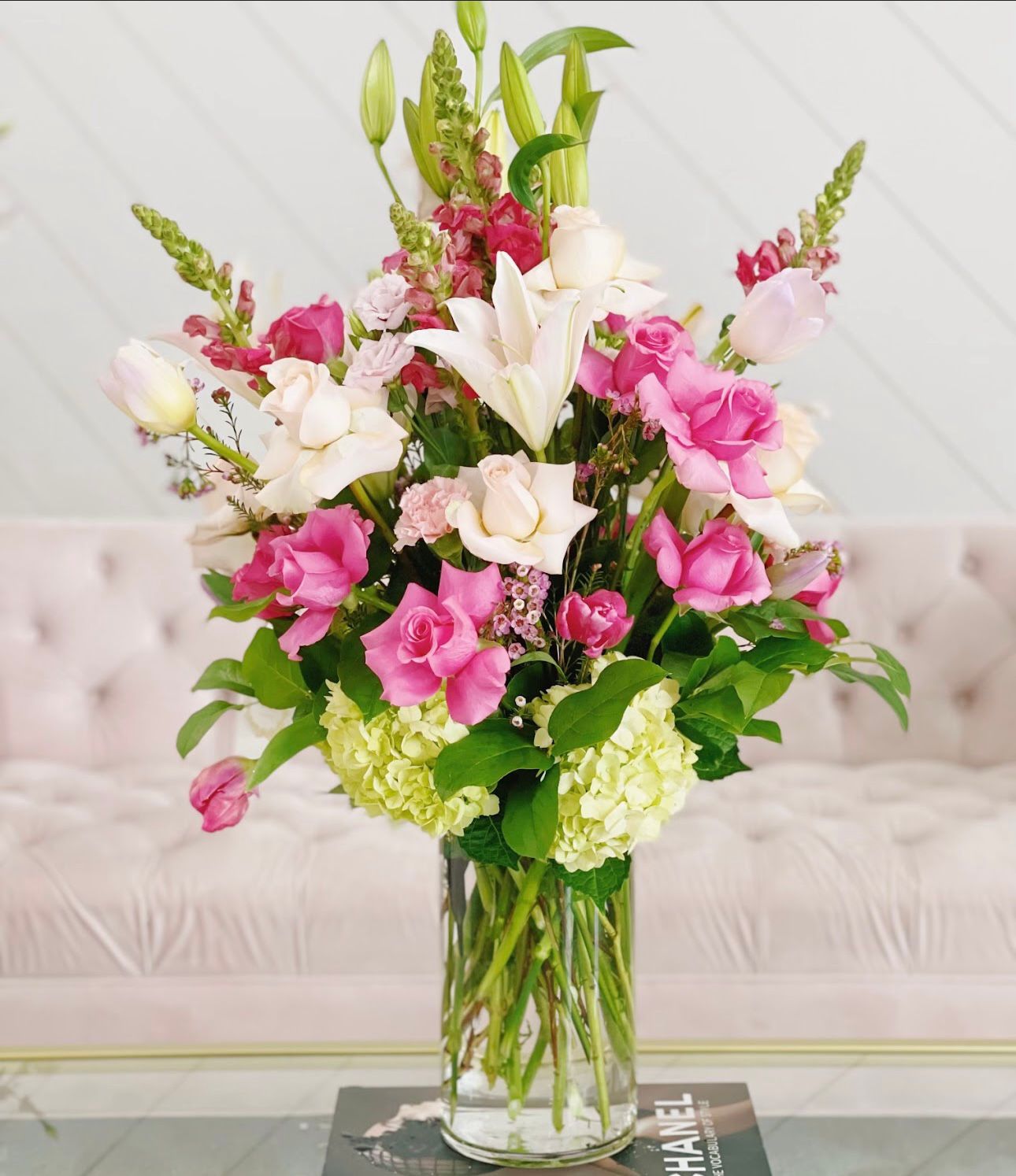 Elegant floral arrangement in a clear vase; pink roses, white lilies, and green hydrangeas.
