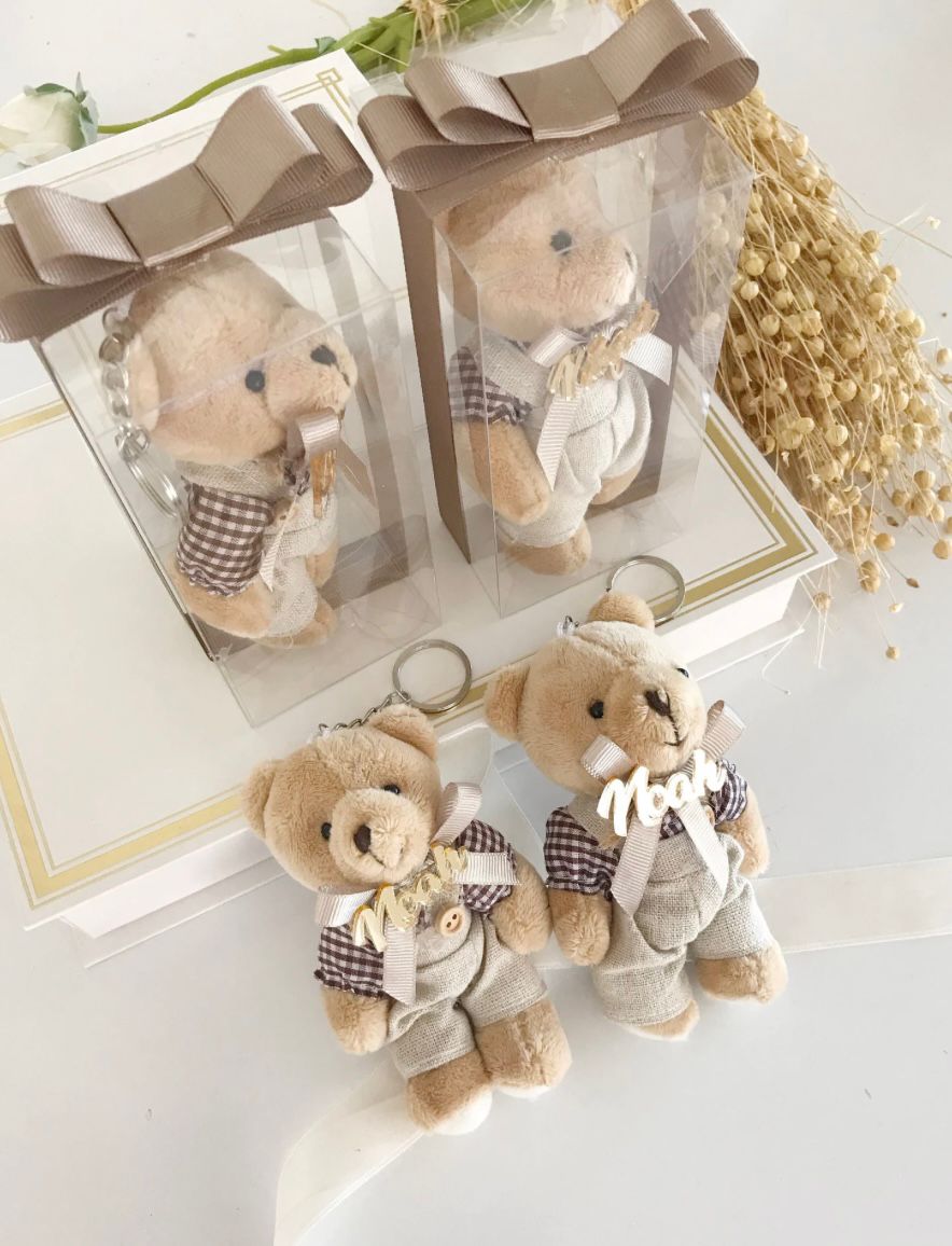 Teddy bear keychains in transparent boxes with ribbon bows.