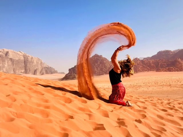 Traveler watching the sunset over the red sandstone mountains of Wadi Rum, Jordan