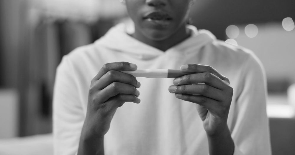 Person in a white shirt holding a small card or note in front of their chest.